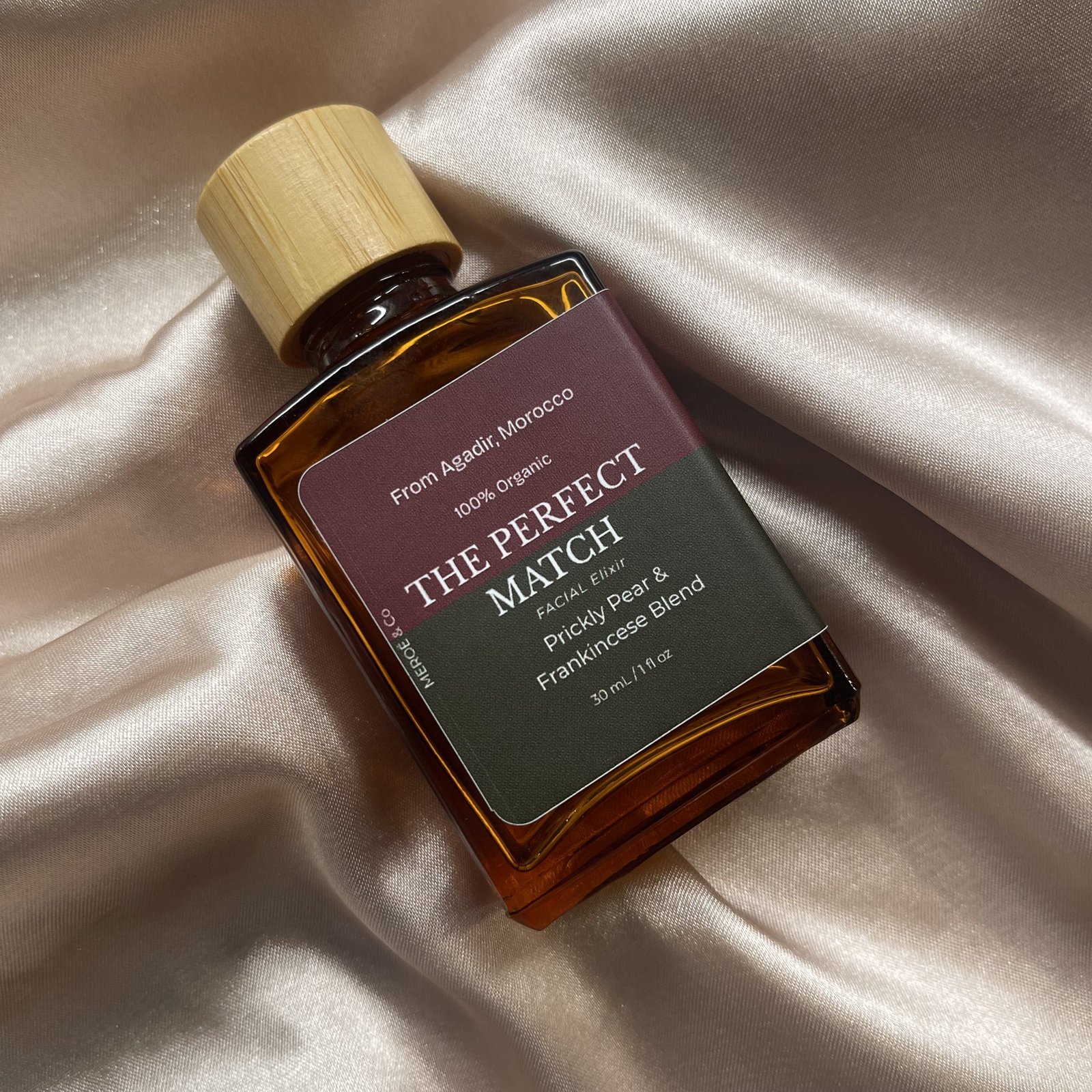 The Perfect Match facial elixir resting on champagne silk